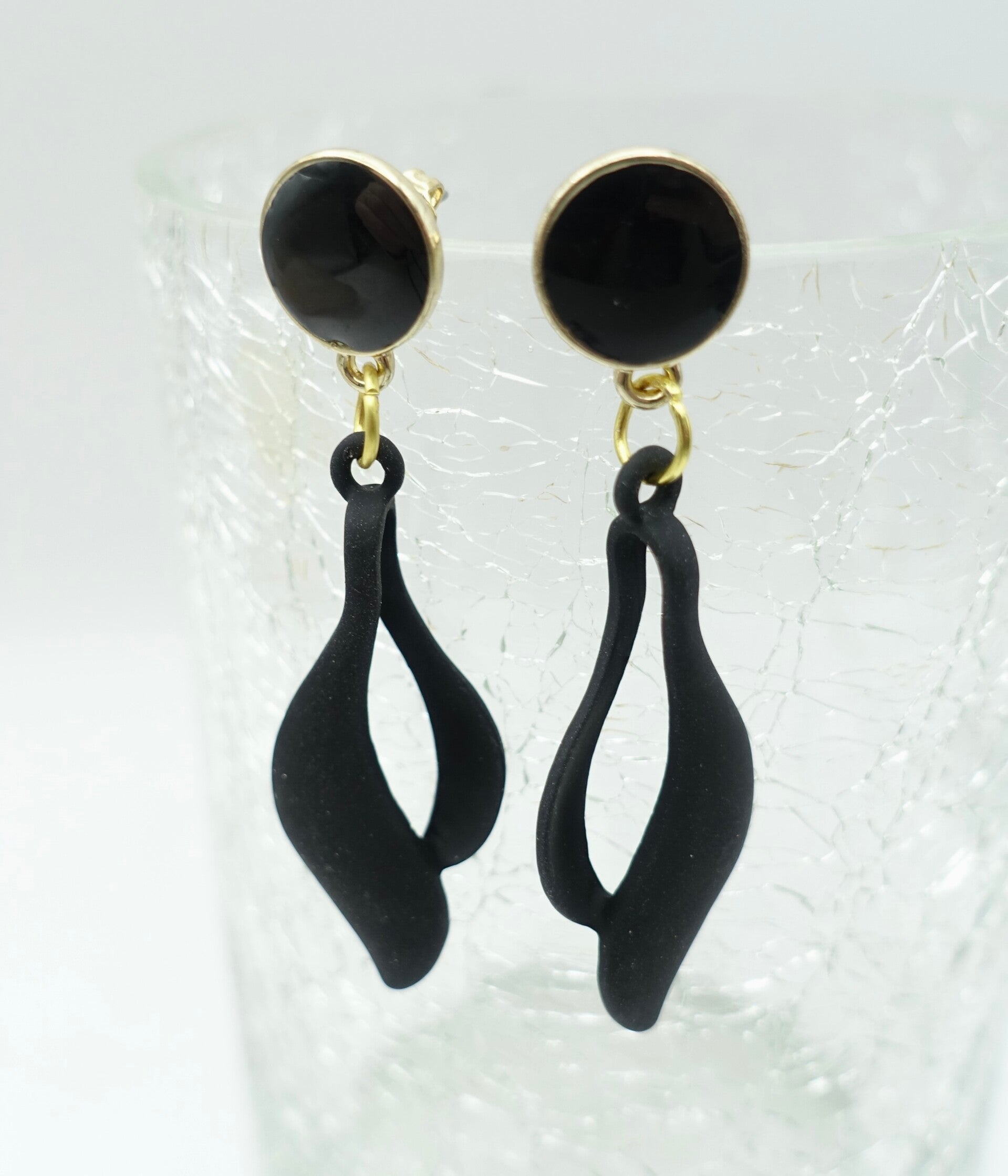 OBzw015024: Zwarte, golvende oorbellen aan zwart/gouden stekers.