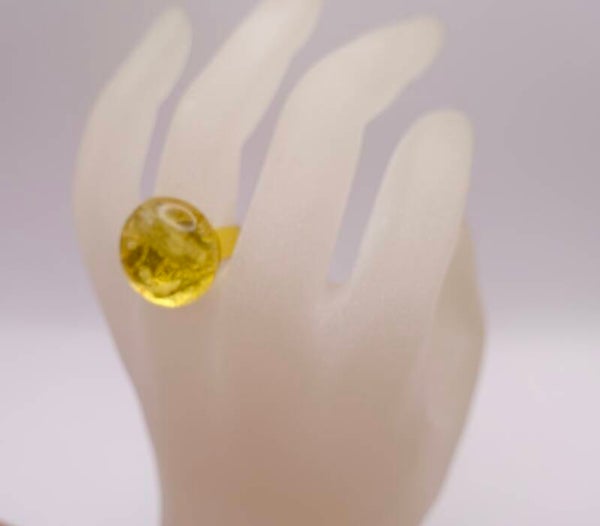 Rigo022625: Goudmetalen ring in transparant geel/goud glas.