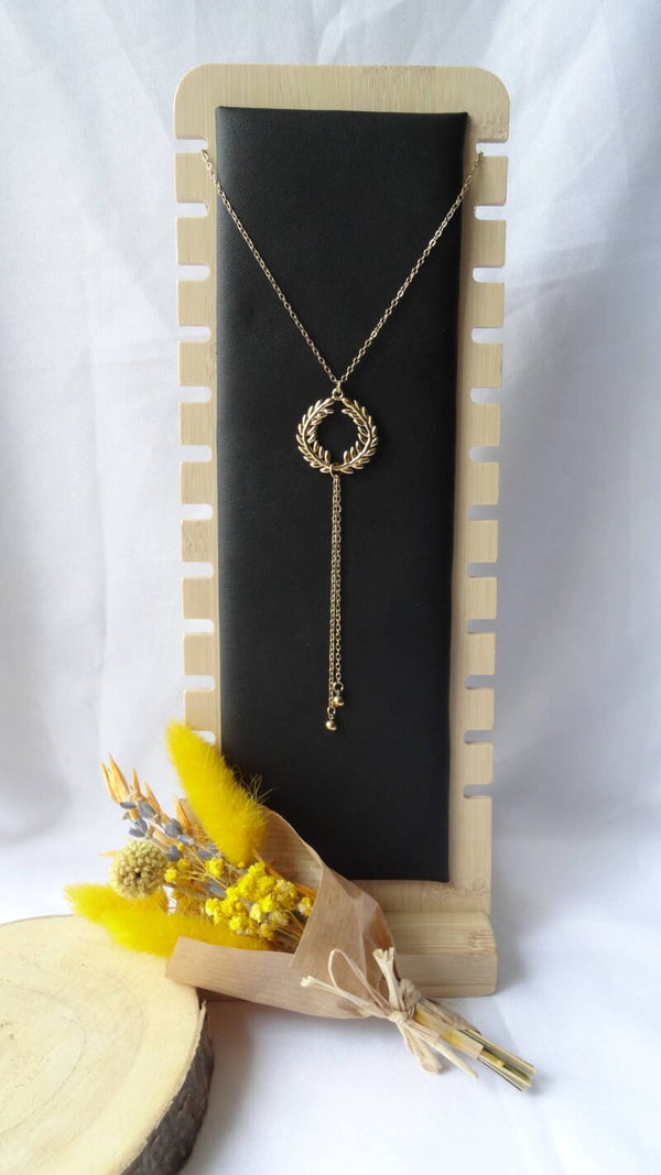 Collier doré long avec un médaillon représentant des feuilles de Laurier.