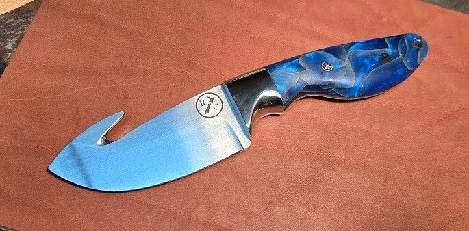 A robust gut hook hunting knife with a blue handle and large bolster.