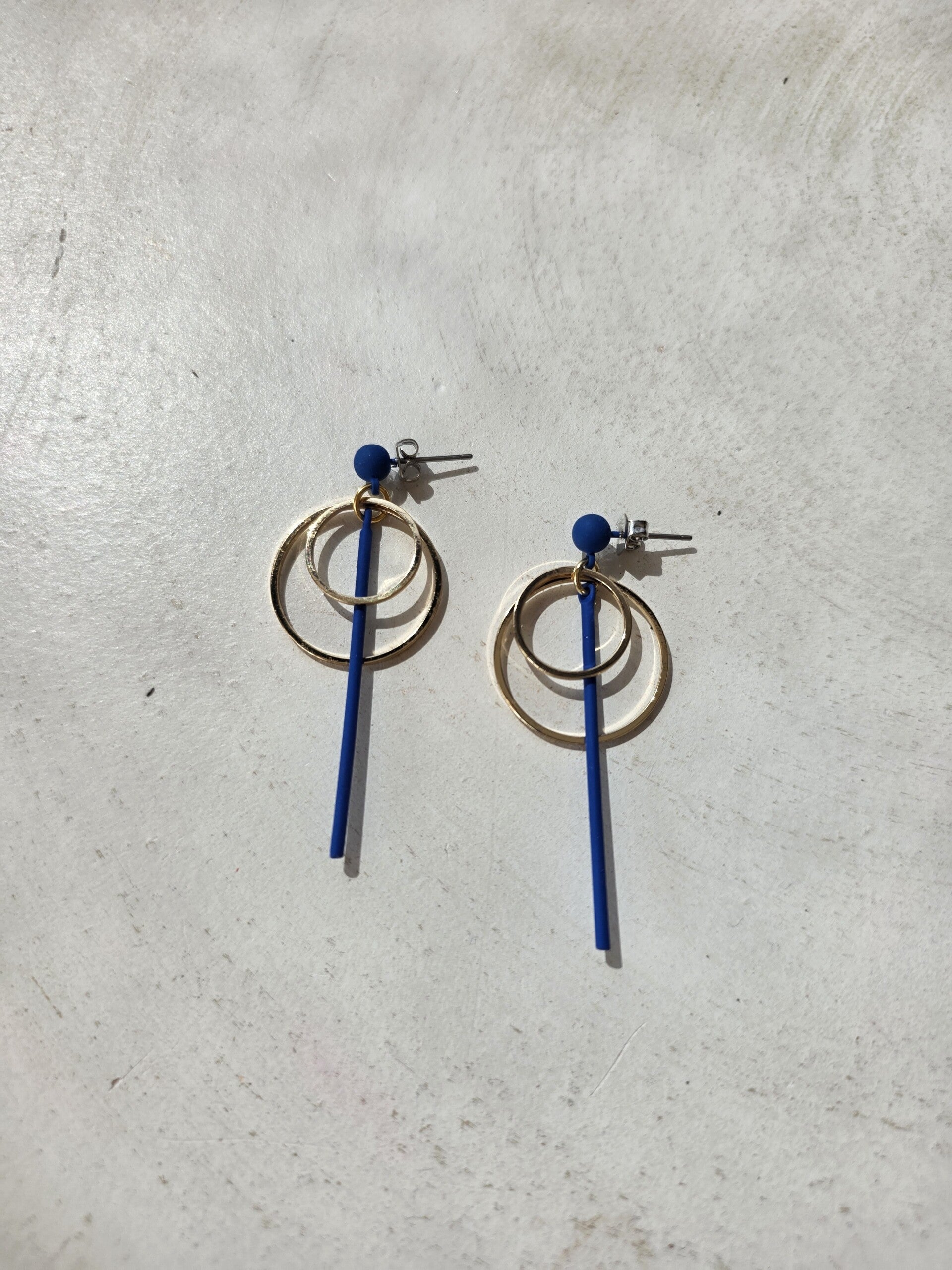 Lange koningblauwe oorbellen (oorstekers) met gouden cirkels.