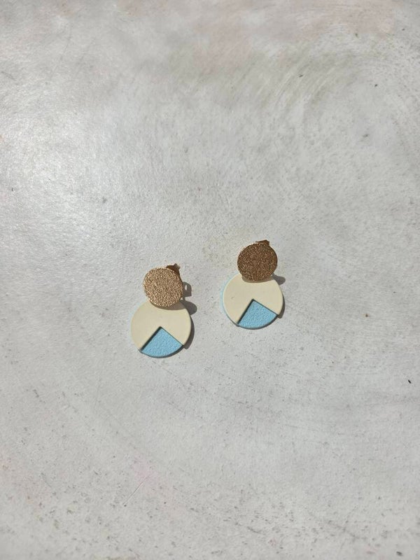 kleine cirkelvormige oorbellen in goud, wit en lichtblauw.