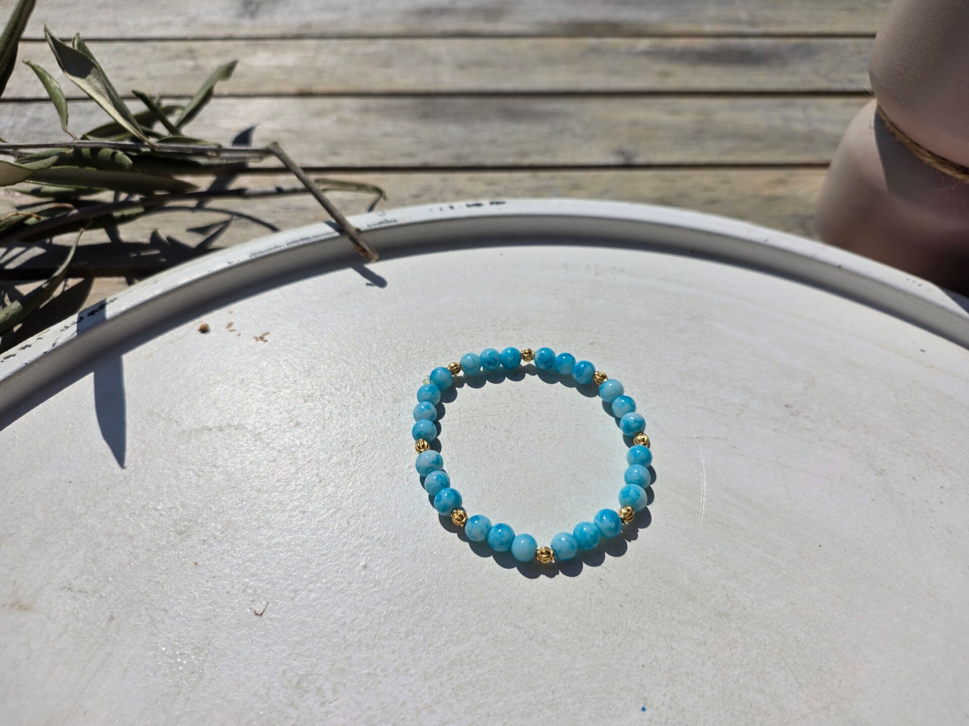 armband uit lichtblauwe ronde kralen afgewerkt met gouden kralen