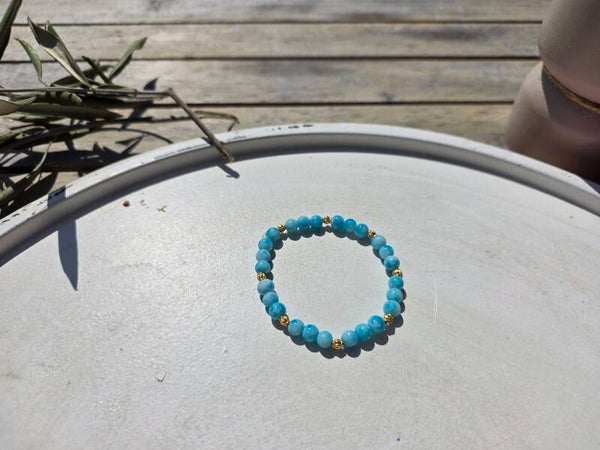 armband uit lichtblauwe ronde kralen afgewerkt met gouden kralen