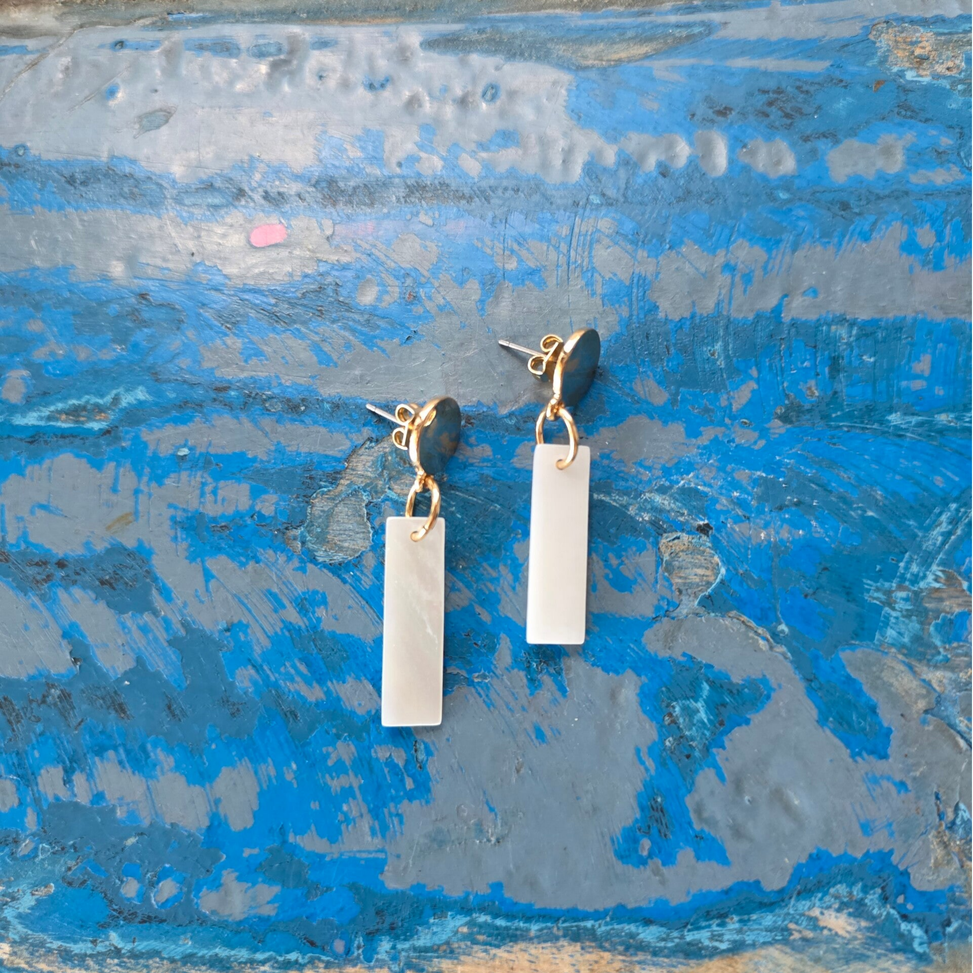 gouden cirkelvormige oorsteker met witte rechthoekige hanger