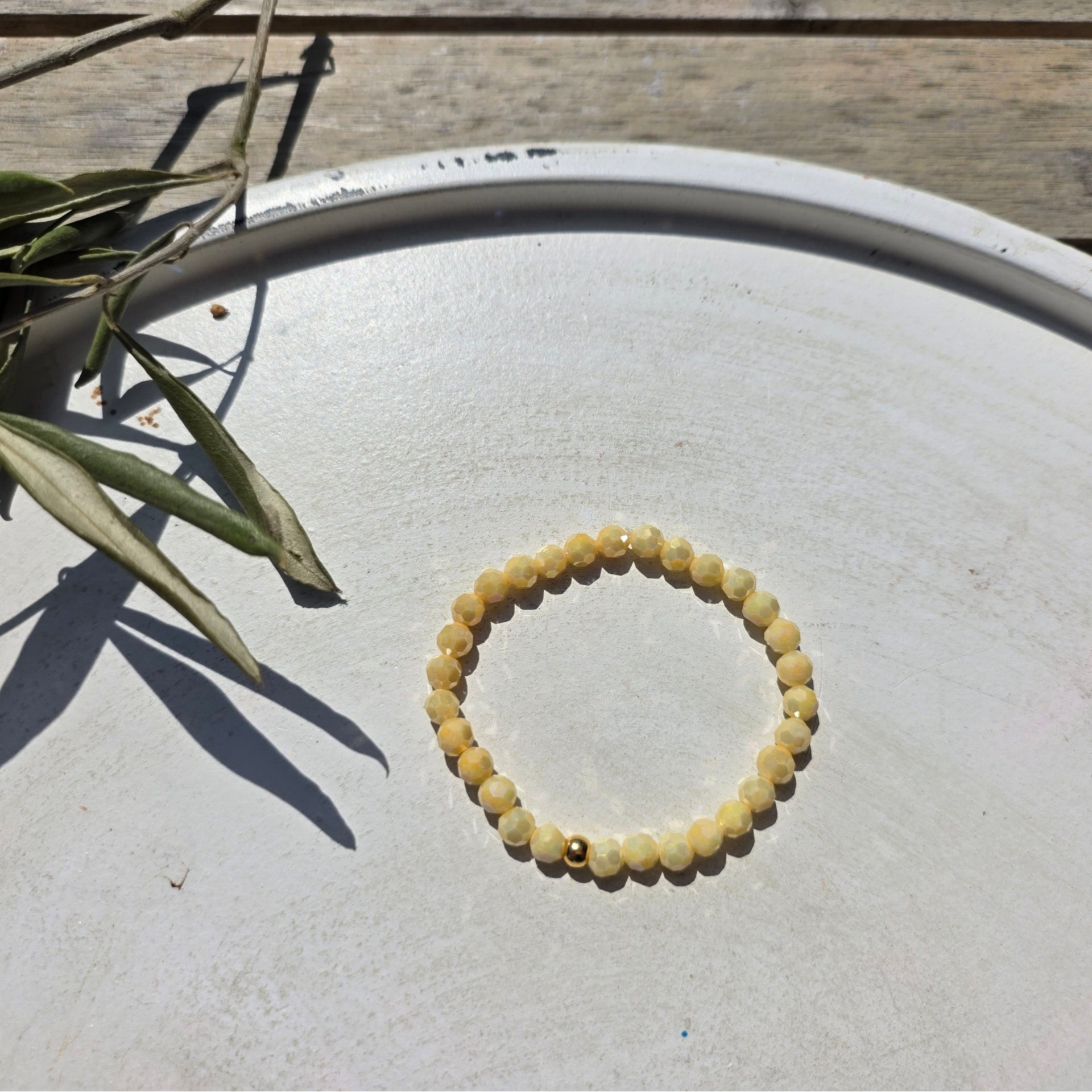 armband uit botergele facetkralen (4mm) afgewerkt met een gouden kraal.
