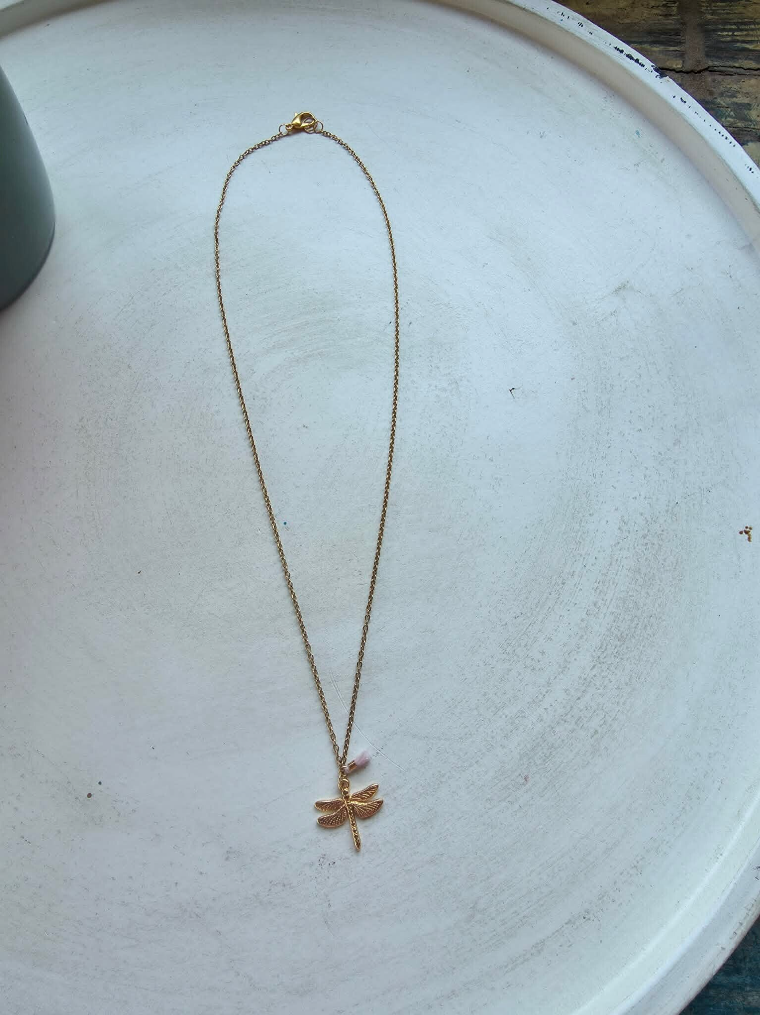 ketting in goudkleur met 2 bedeltjes (roze kwastje en libel)