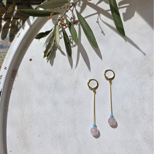 oorbellen met een slanke hanger en rozenkwarts edelsteen afgewerkt met een klein turquoise kraaltje.
