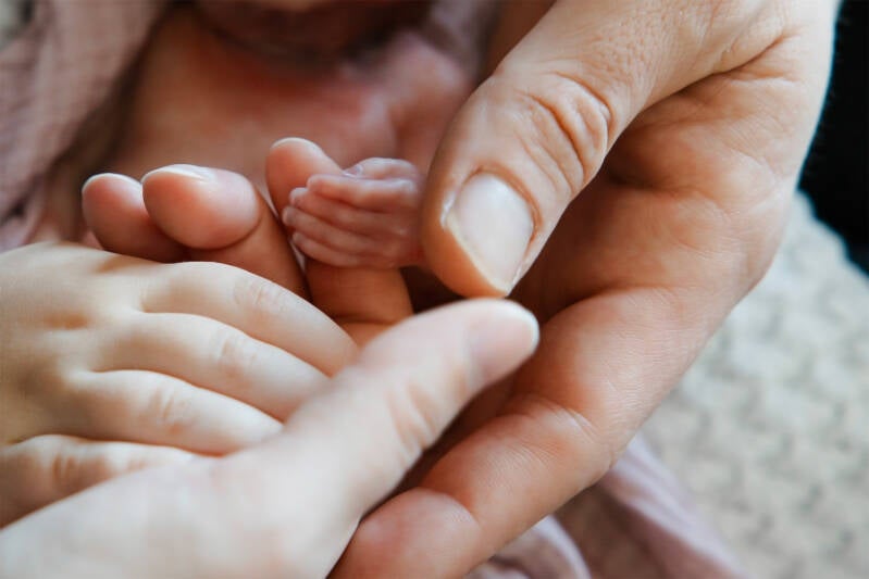 Volwassene raakt voorzichtig babyhandje aan