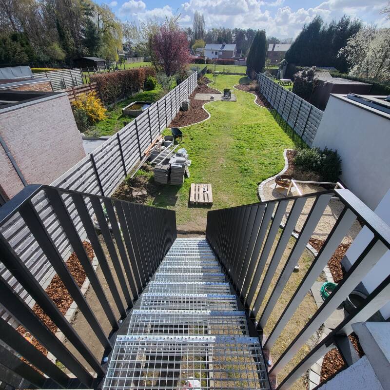 Stalen buitentrap voorzien van spijlbalustrades, afgewerkt in metalliseren + poederlak RAL 9005