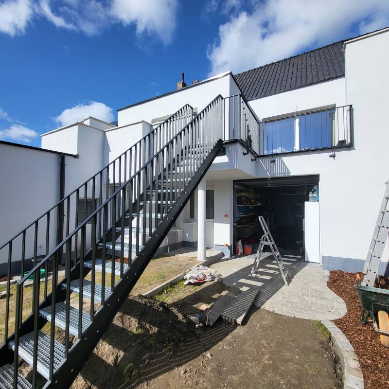Stalen buitentrap voorzien van spijlbalustrades, afgewerkt in metalliseren + poederlak RAL 9005