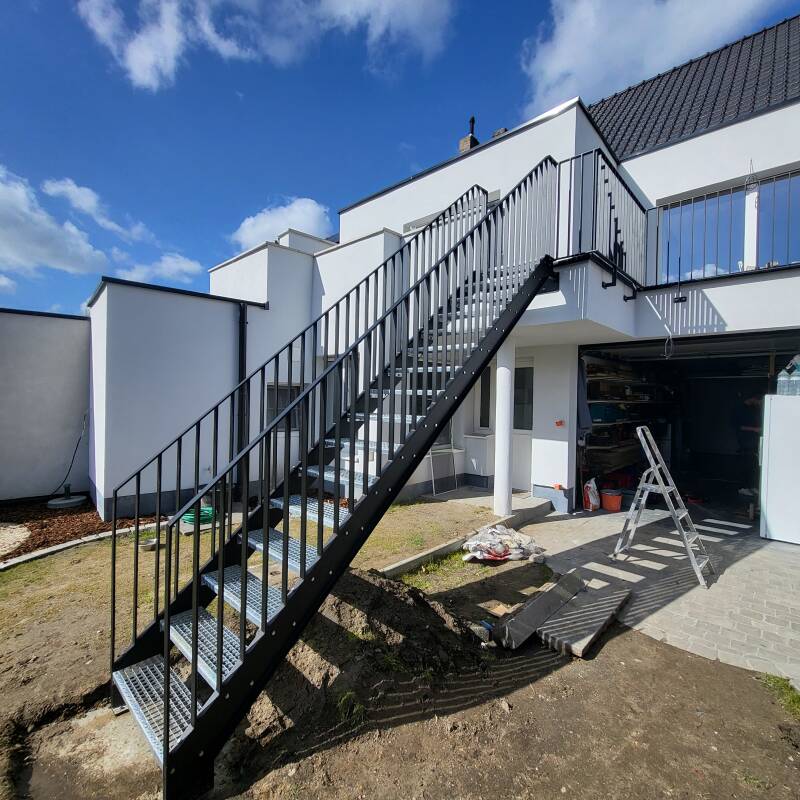 Stalen buitentrap voorzien van spijlbalustrades, afgewerkt in metalliseren + poederlak RAL 9005
