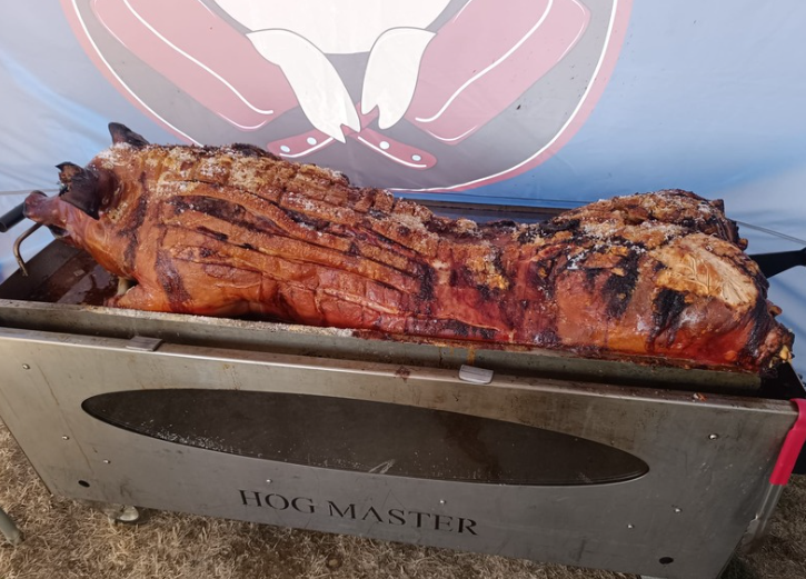 Close-up of a hog roast machine with golden-brown pork turning on a spit
