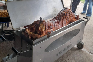 Close-up of a hog roast machine with golden-brown pork turning on a spit