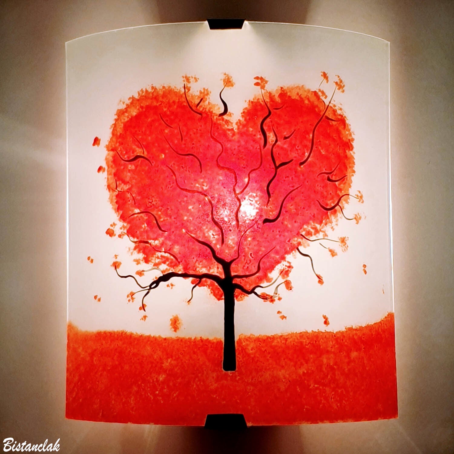 une applique murale blanche en verre décorée d'un arbre au feuillage rouge en forme de coeur