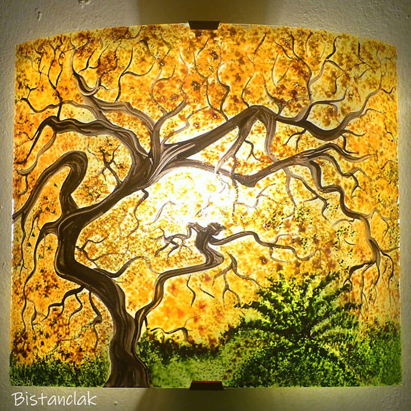 Applique murale décorée d'un paysage représentant un arbre tortueux au feuillage orangé, ce luminaire est une variante du modèle Arbre de printemps.