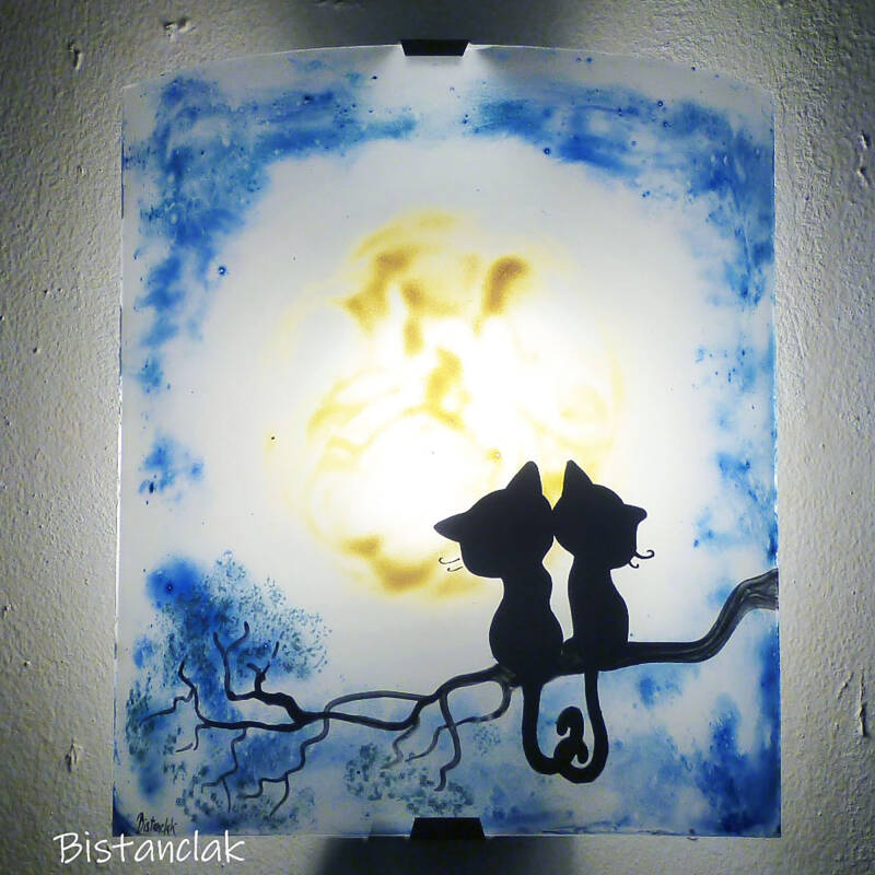 applique murale artisanale en verre à l'abat-jour en demi-cylindre décoré de deux chats sous une grosse lune jaune dans un ciel bleu foncé.