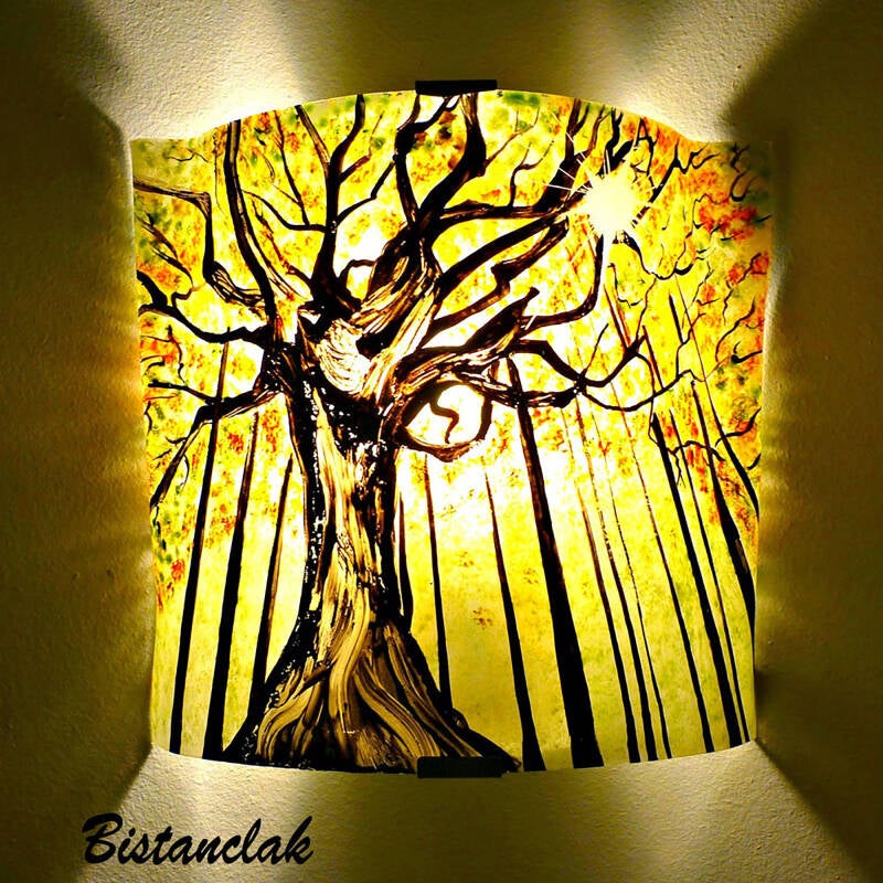 lampe murale décorative, ce luminaire représente un paysage, un arbre imposant en lisière de forêt au feuillage jaune et vert