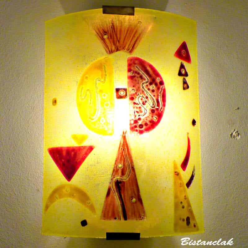 cette applique murale en verre est colorée de jaune et de rouge foncé, avec un décor composé de pièces géométriques à la manière de Kandinsky.