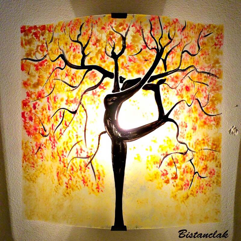 cette applique en verre est colorée de jaune pastel et décorée de l&#039;arbre danseuse au feuillage rouge et jaune.