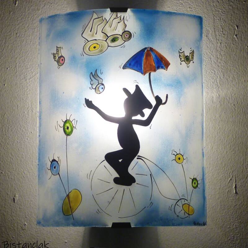 cette lampe murale au motif fantaisie représente un bonhomme avec un chapeau haut-de-forme sur un étrange vélo.