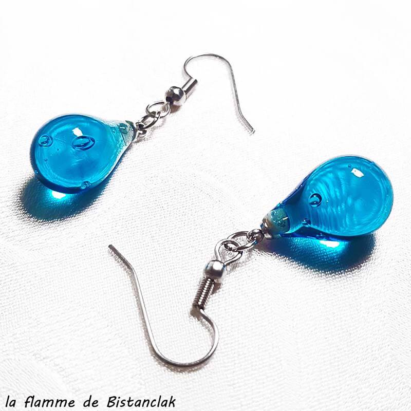 ces boucles d'oreilles artisanales en verre sont façonnées en forme de goutte d'eau de couleur bleu turquoise transparent.