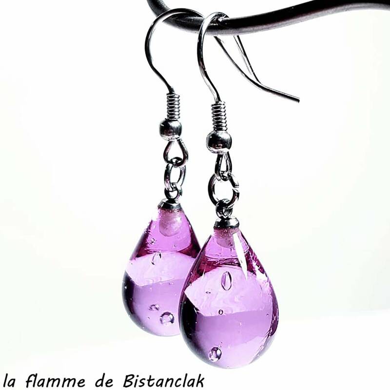 une paire de boucles d'oreilles en forme de goutte d'eau de couleur rose transparent en verre, elles sont suspendues par leur crochet en acier.