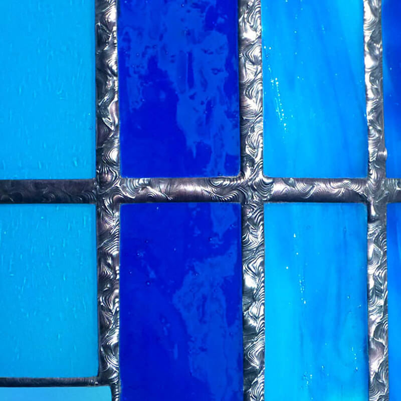 détail des finitions décoratives sur les souduires d'une applique vitrail bleue