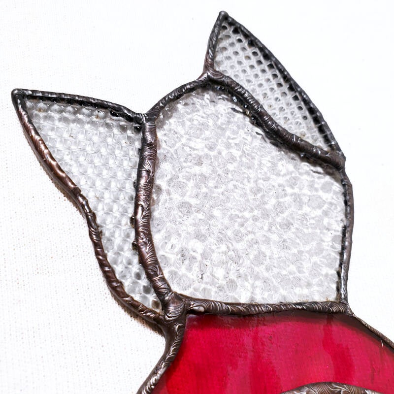 zoom sur la tête du chat comportant deux types de verres incolores structurés, le granité et l'imprimé cube, et le collier en verre rouge.