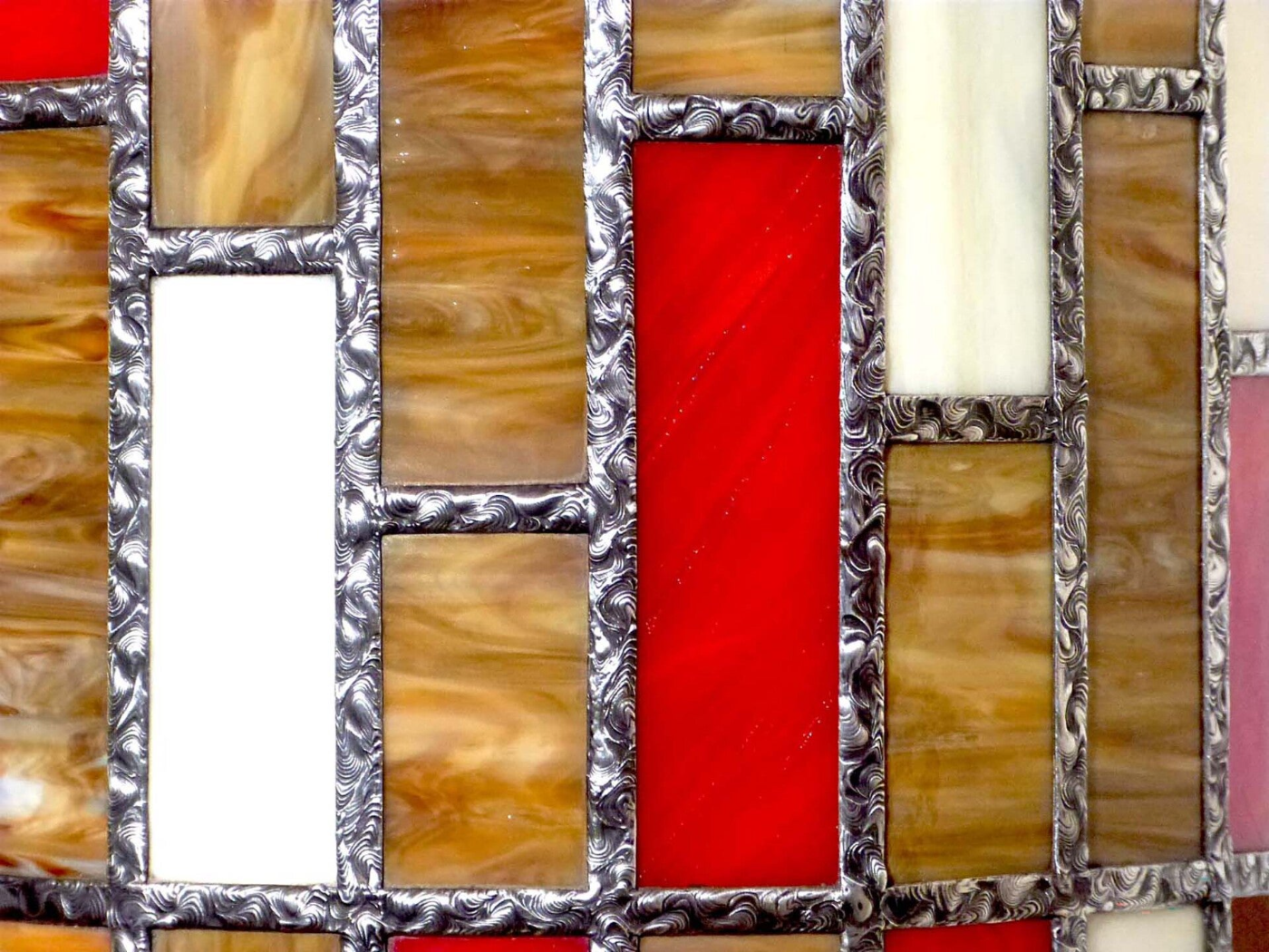 les pièces de verre composant le luminaire sont séparés par le ruban étamé qui présente les motifs aléatoires.