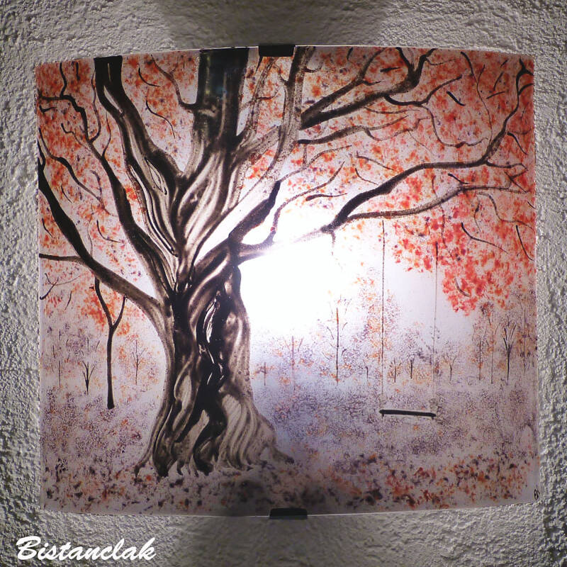 Applique murale personnalisée décorée du paysage d'une simple balançoire accrochée à la branche d'un arbre imposant au feuillage rouge et mauve, avec quelques arbres diffus en  arrière plan.