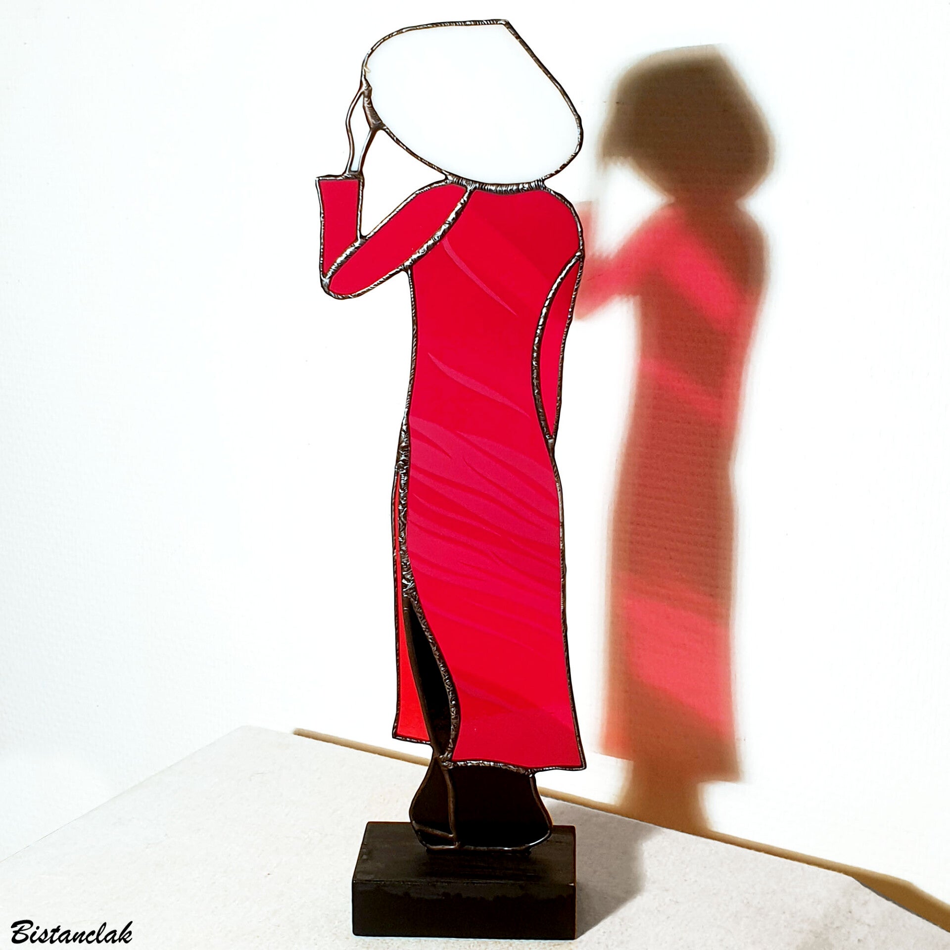 un objet vitrail Tiffany représentant une femme en tenue traditionnelle vietnamienne au chapeau conique blanc, à la robe fendue rouge sur un pantalon noir.
