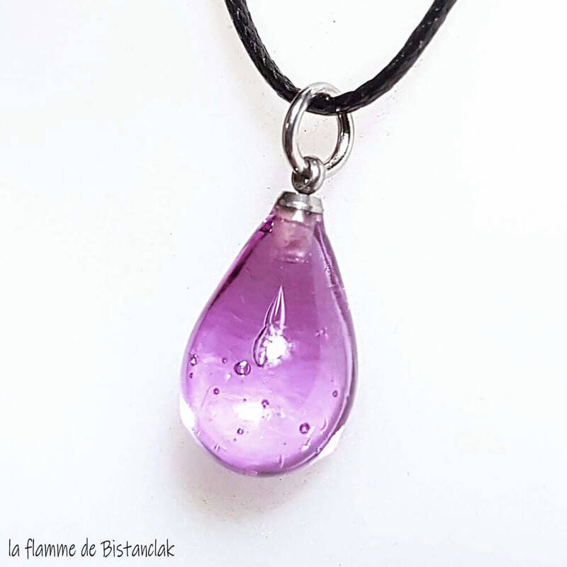 une goutte d'eau en verre rose transparente montée sur un cordon noir