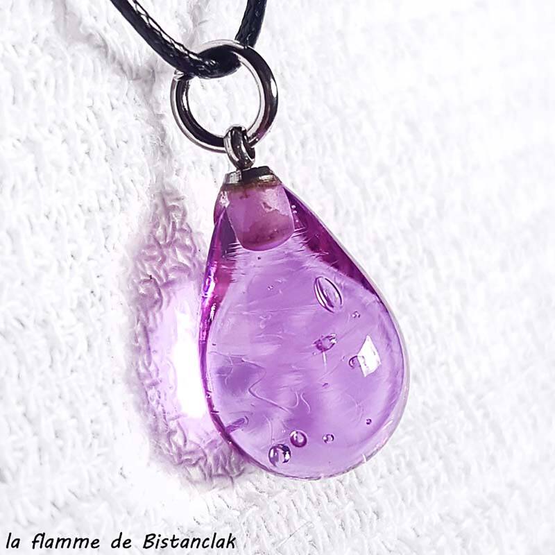 un pendentif en verre filé en forme de goutte d'eau de couleur rose soutenu transparent