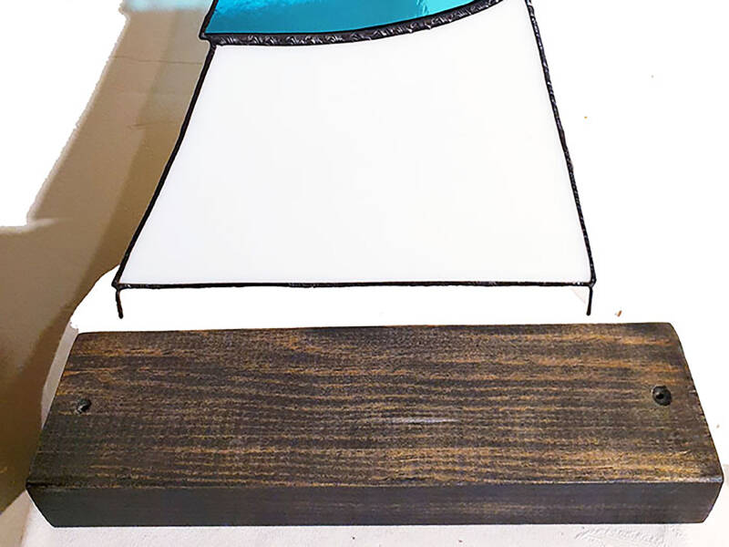illustration du socle en bois teinté et percé pour insérer les tiges métalliques soudées en bas de la déco vitrail.
