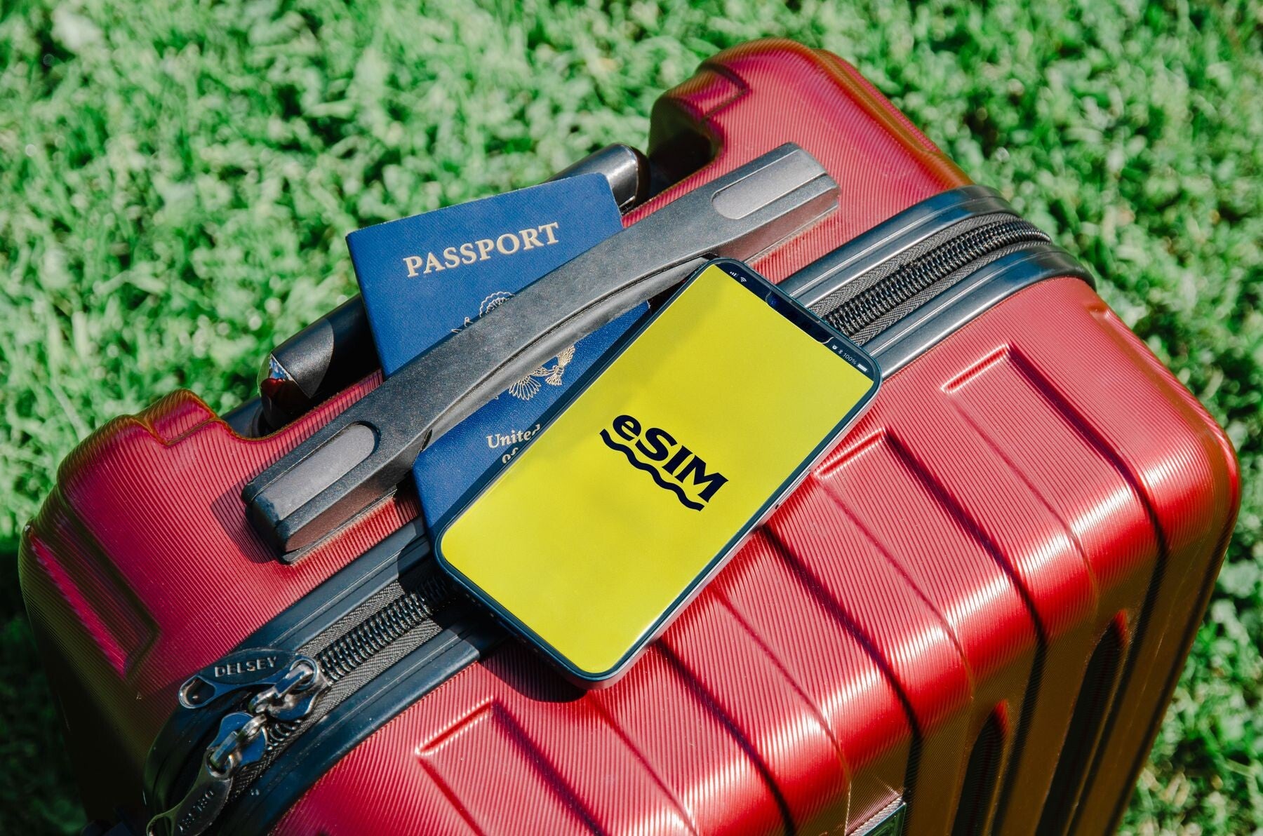 A passport and smartphone resting on a red suitcase, representing cruise documents and embarkation-day preparation.