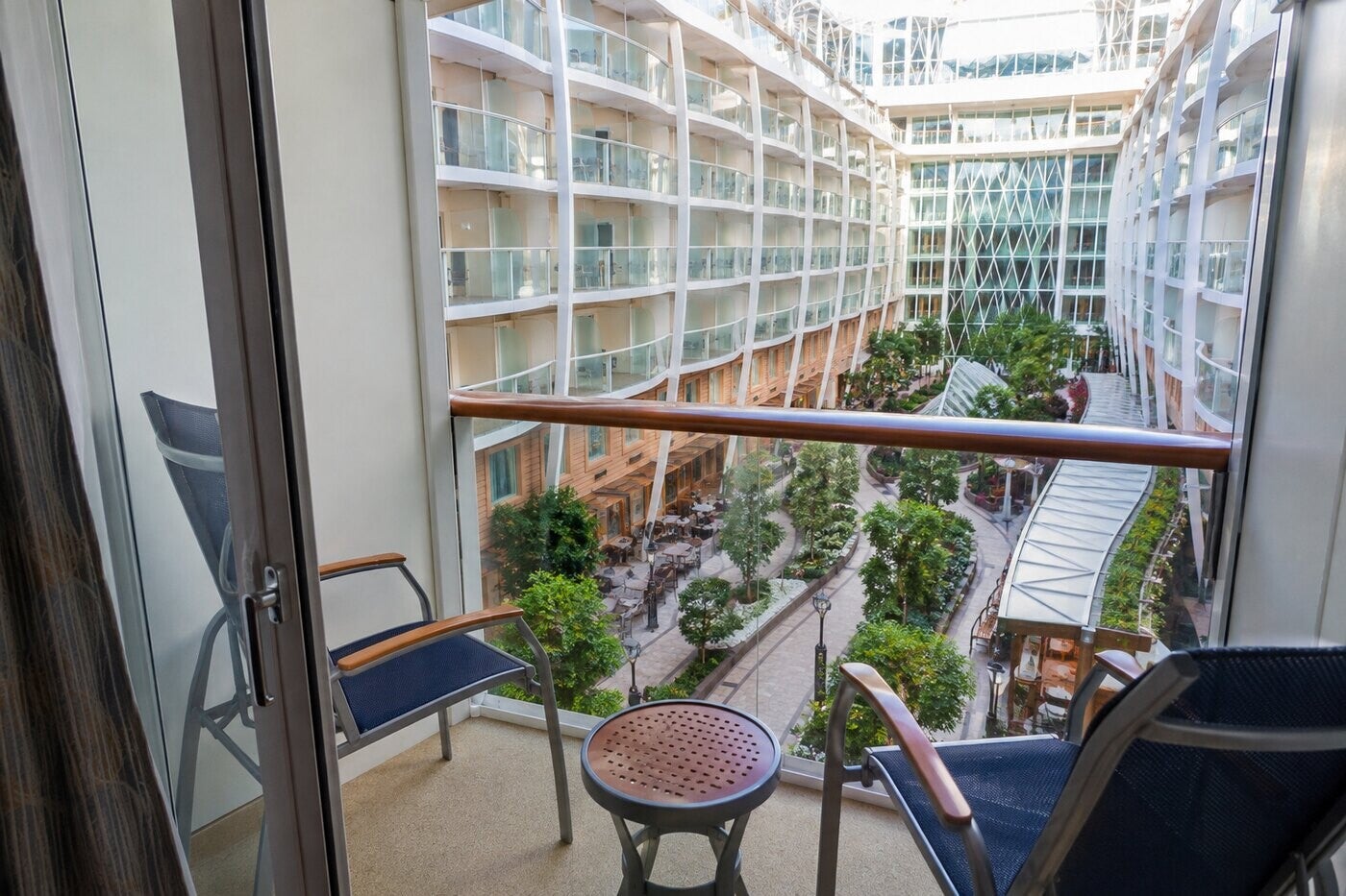 Cruise-ship balcony cabin with private outdoor seating and an ocean view