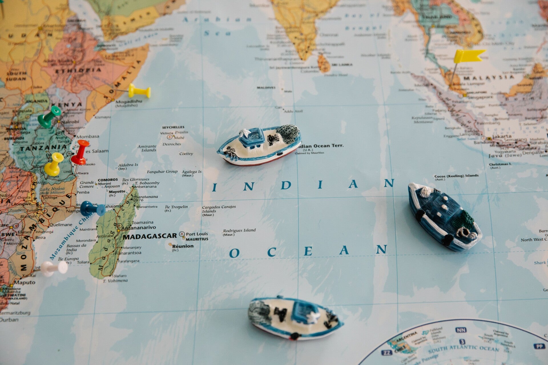 Small model ships and colored pins arranged on a world map to represent comparing cruise routes.