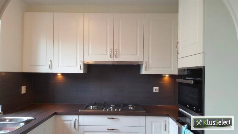 Witte keuken met donkere achterwand en inbouwapparatuur