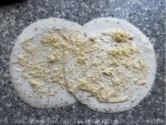 3. Strooi geraspte kaas over de kaassaus