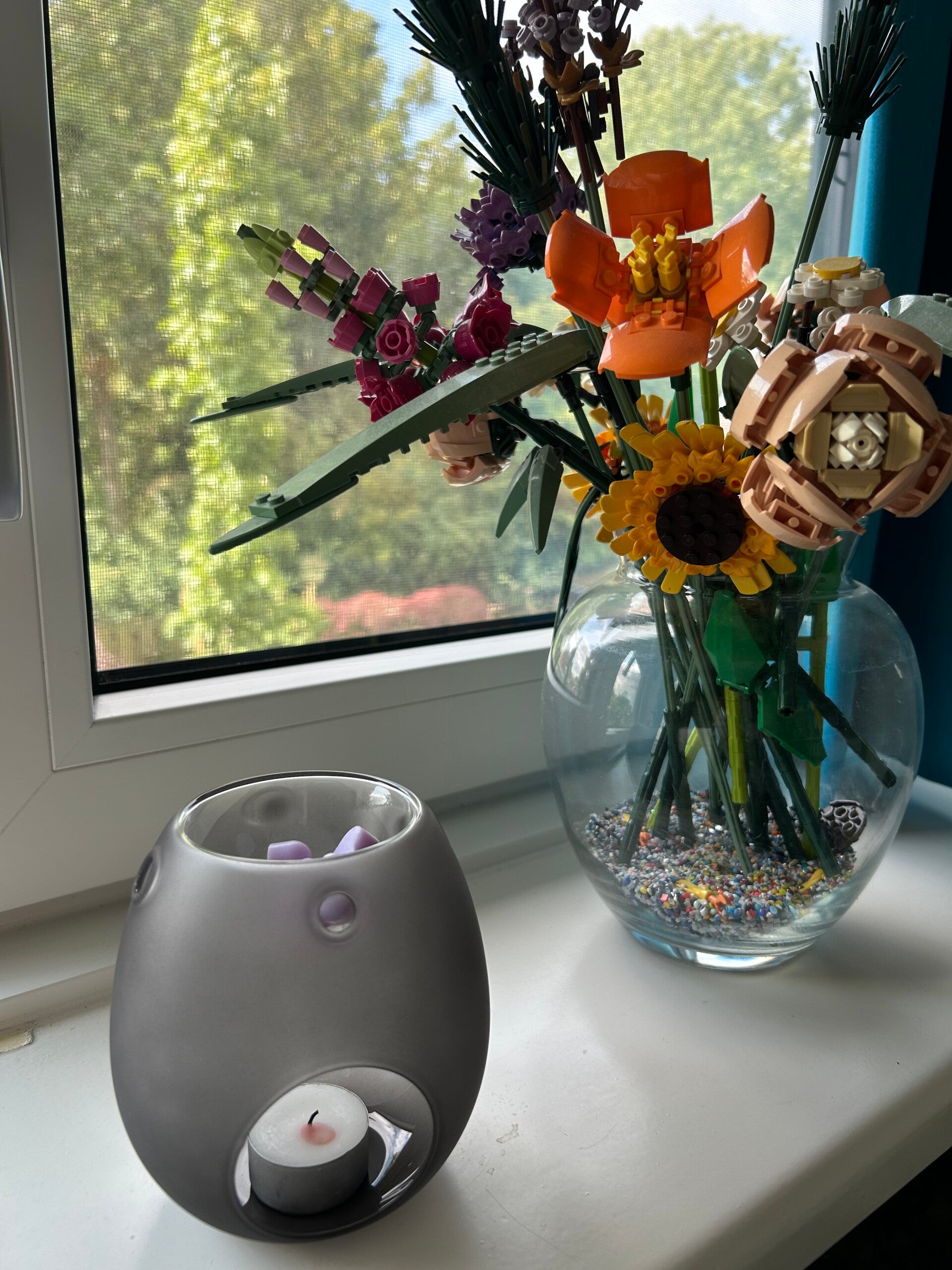 Een waxbrander met een eigen gegoten waxmelt erop bij een vaas met lego bloemen