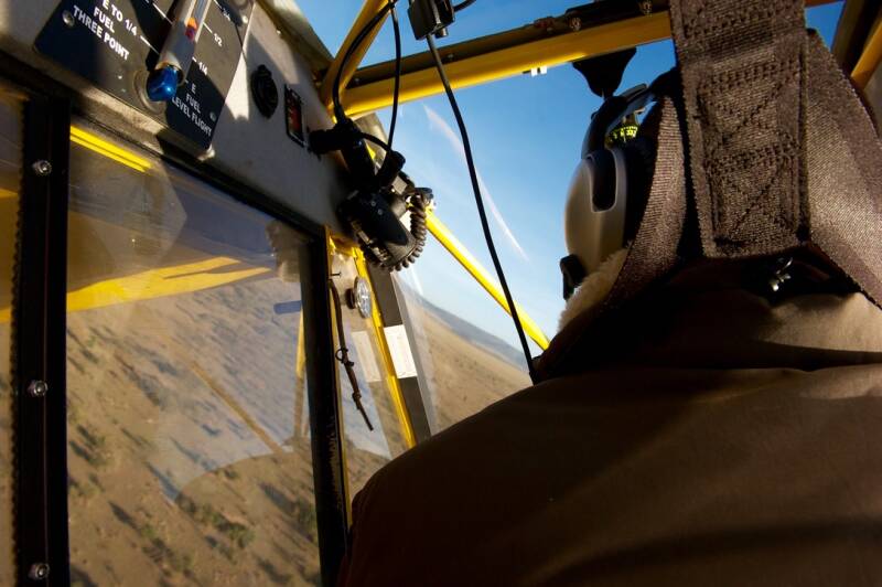 Inside yellow Super Cub cockpit during steep bank turn over Maasai Mara, Kenya, flown by Marcel Romdane on a Fly4Elephants morning patrol mission — aerial conservation in chaos mode.