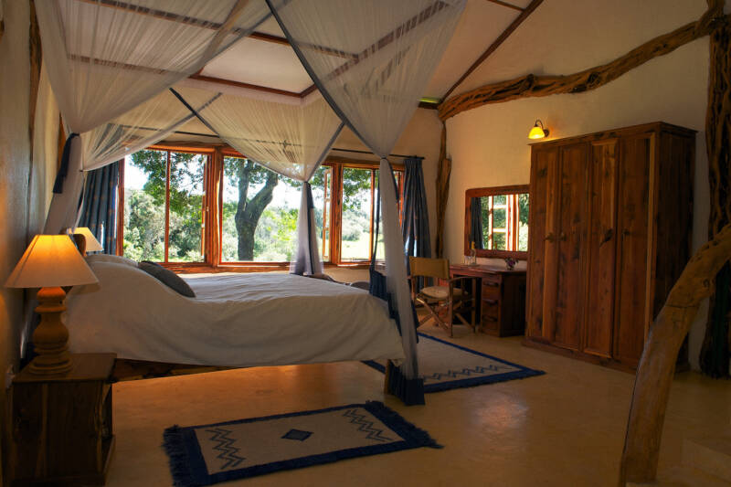 Luxury safari cottage bedroom in Mara North, Kenya, with canopy bed and forest view—featured in Romdane’s memoir What Could Possibly Go Wrong?, blending dark humour, absurd survival, and Campfire Syndicate storytelling chaos.