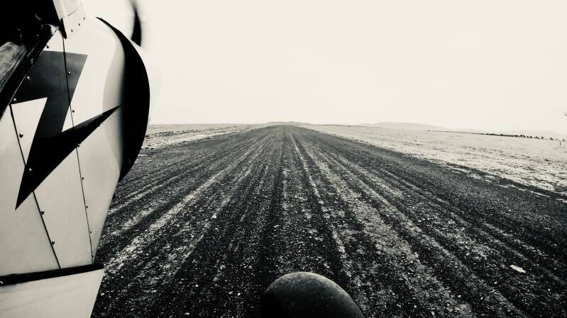 Runway view from Marcel Romdane’s Piper Super Cub in Kenya, looking down a remote bush airstrip toward the horizon. Silvertone conservation aviation image representing Fly4Elephants, rough-field flying, and the next chapter of aerial conservation work in 