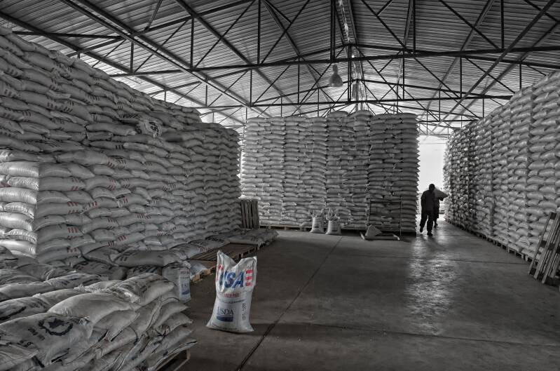 Towering USAID food aid bags inside a Kenyan warehouse. Photo by Marcel Romdane, exposing the theatrical excess and inefficiency of modern charity. From Riches to Rags: An African Odyssey, Part IV / Where Good Intentions Go to Die. 