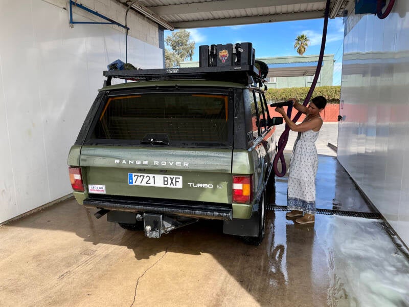 Range Rover Classic being washed in Arizona by Marcel Romdane’s wife — a moment of false hope before discovering what horrifying mechanical truths lay beneath the dirt, as told in What Could Possibly Go Wrong.