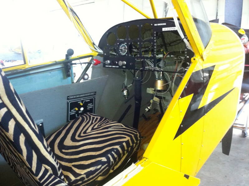 Unfinished Super Cub cockpit with zebra print seats and missing instruments — bush flying chaos from Marcel Romdane’s African memoir From Riches to Rags, Chapter 11