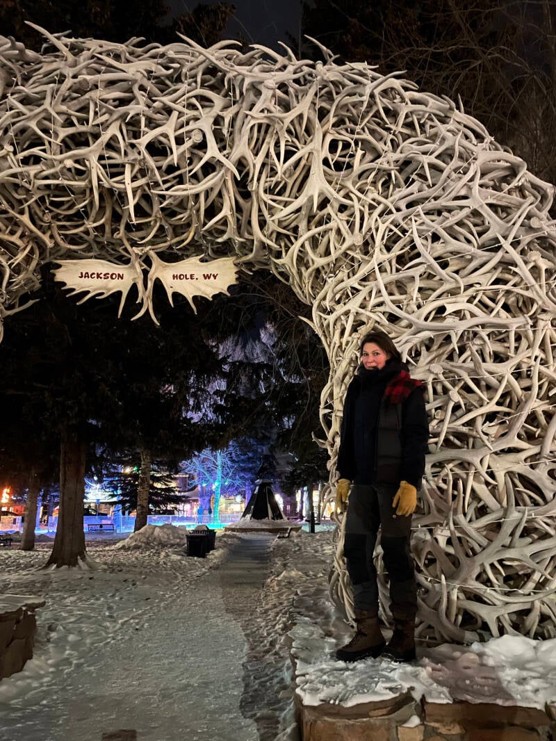 Jackson Hole, Wyoming — Nicole Romdane under the infamous elk antler arch, moments after the evening imploded into bureaucratic madness. A frozen pause before the slow, soul-curdling return to Thermopolis. From What Could Possibly Go Wrong?.