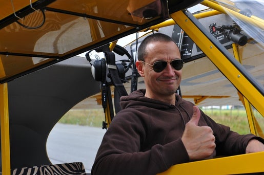 Marcel Romdane gives a delusional thumbs-up inside his yellow Cub. From Riches to Rags: An African Odyssey, Part VIII — Taildraggers, Tantrums, and the Final Nail in Sanity’s Coffin. Zebra seats optional. Sanity not included.