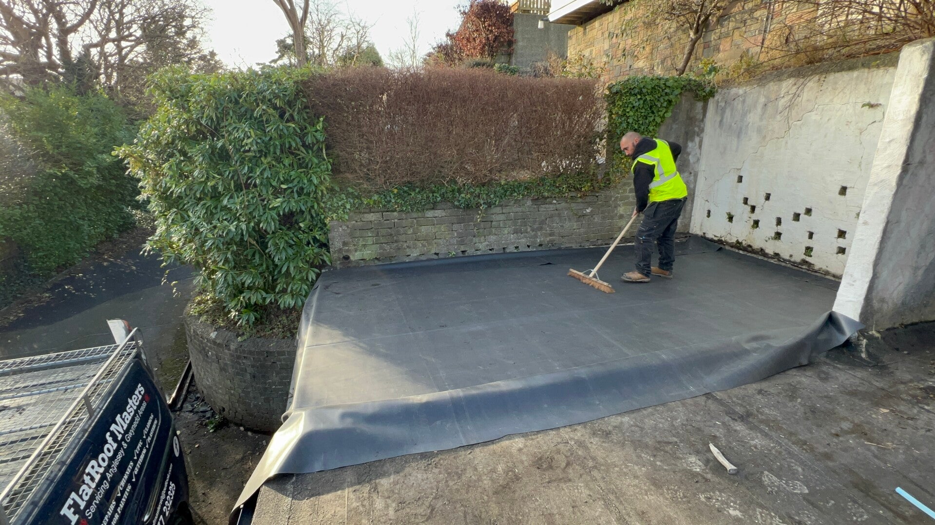 New flat roof membrane installed beside a retaining wall